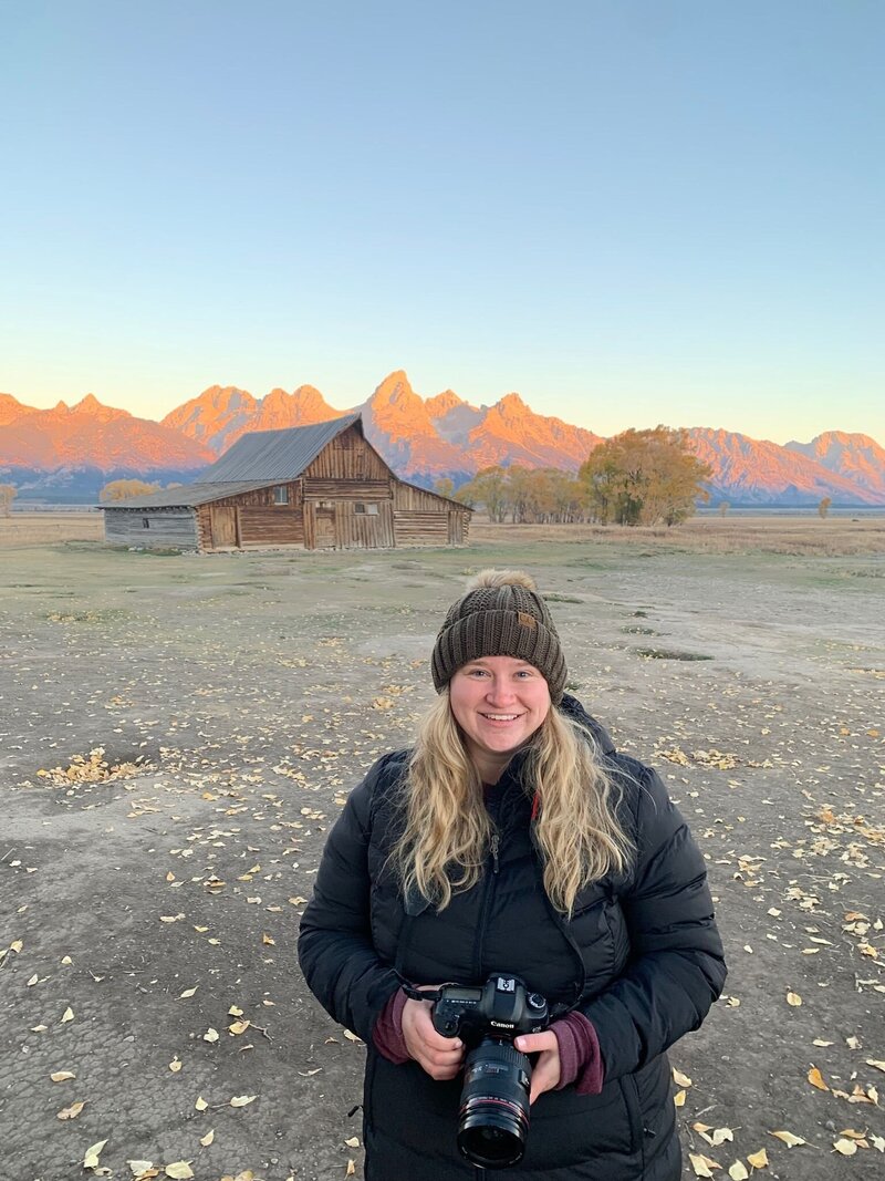Jessica Nicole Photography smiling holding her camera at the Mormon Row Barn in Jackson, Wyoming. Ready to photograph your Colorado wedding.