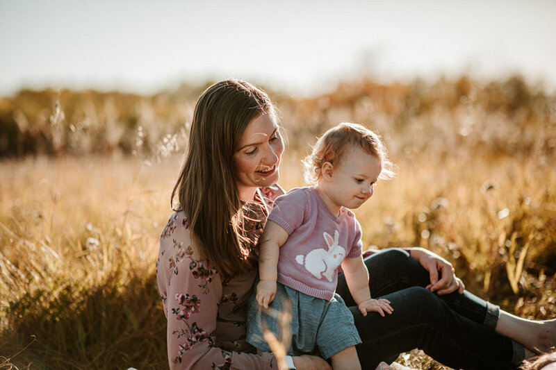 Mom sitting in the prairie grass with young girl at Assiniboine Forest 