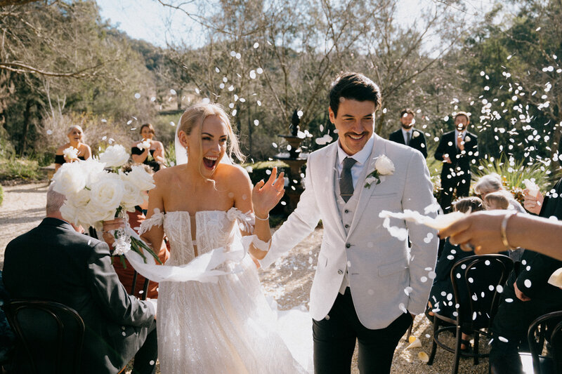 Bride and groom walking down the aisle with confetti at their Wallalong house wedding, Hunter Valley