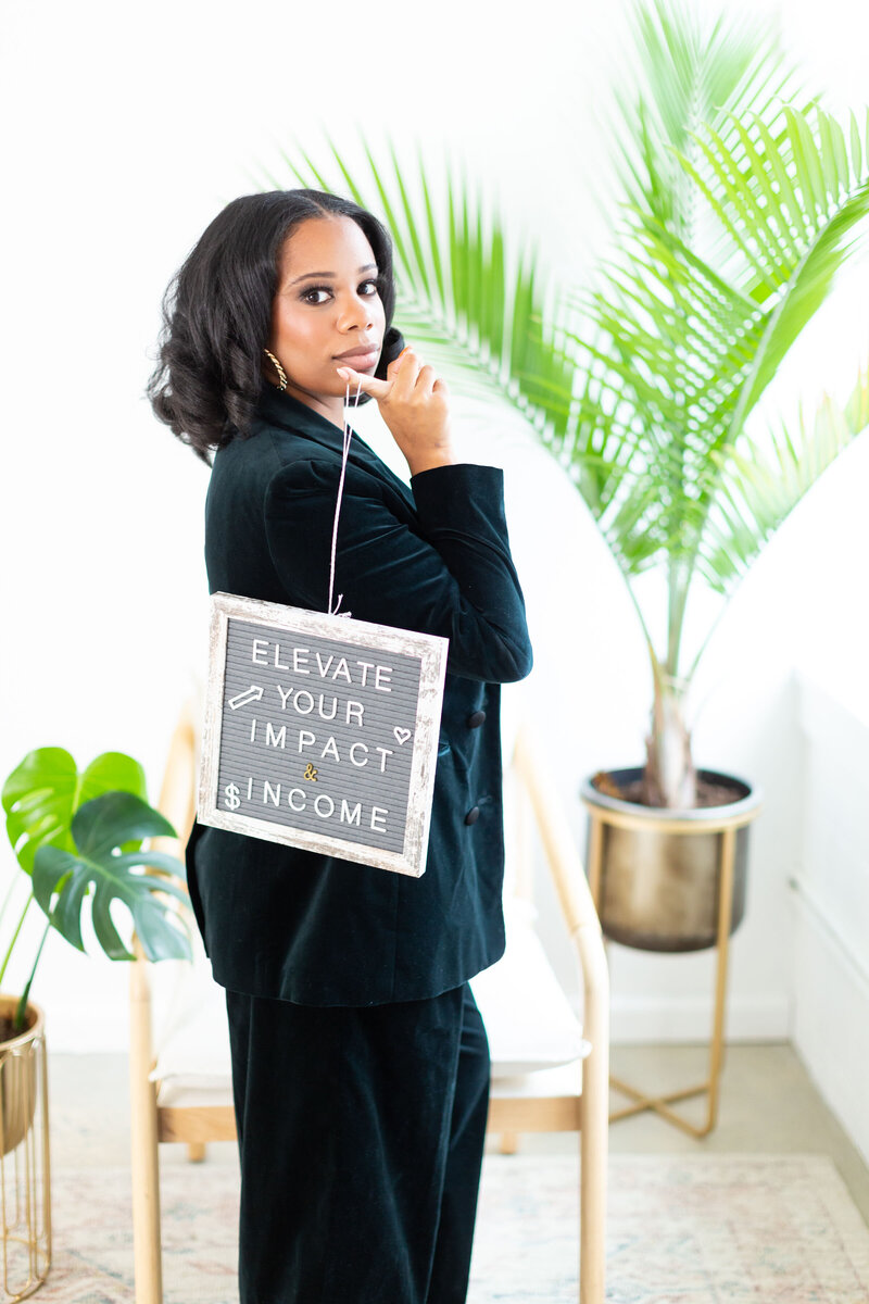 woman holding a sign that says elevate your impact and income