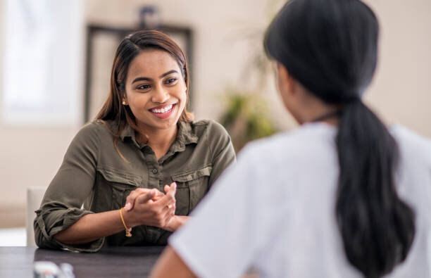 Smiling woman sitting across from another woman