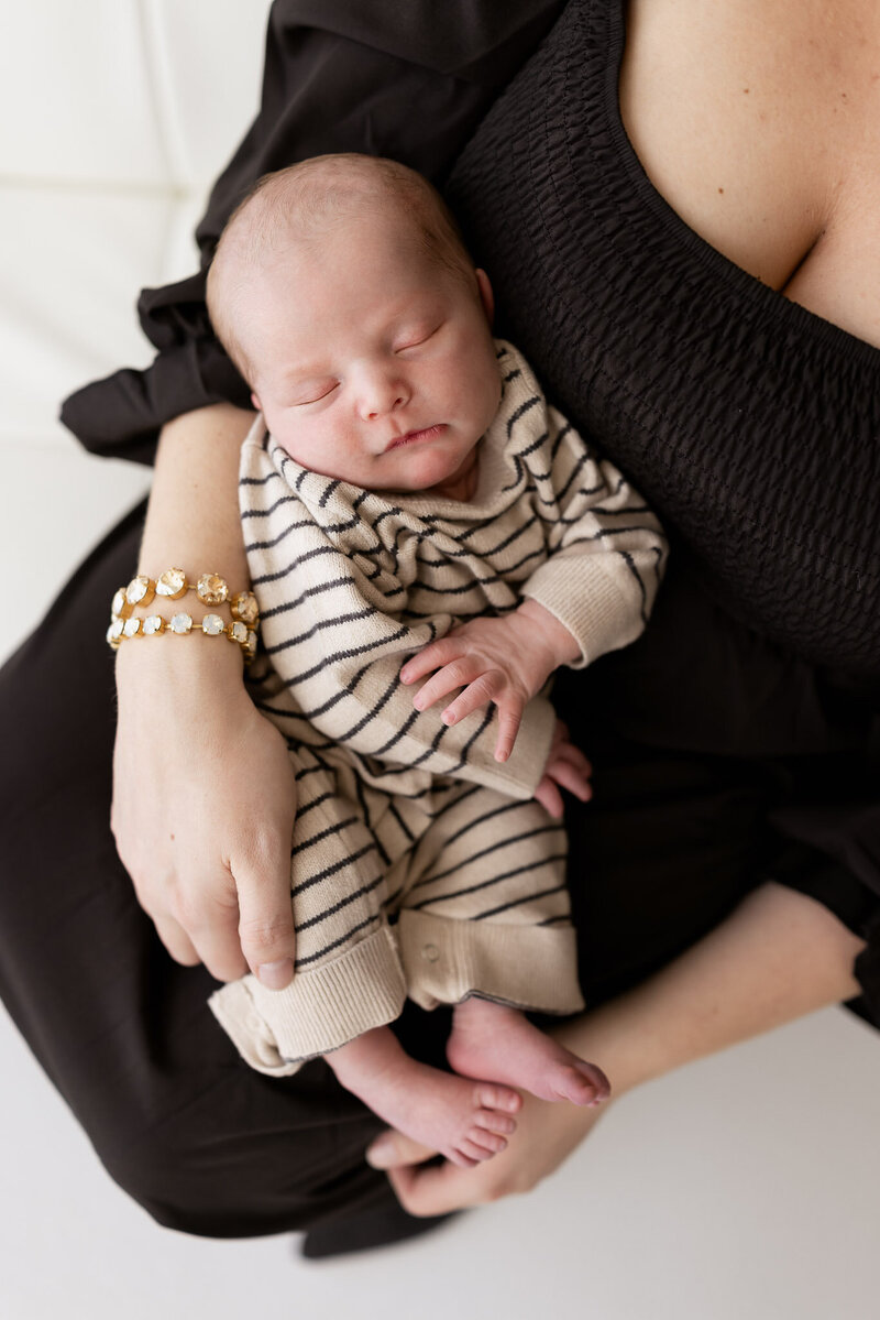 Mom holding newborn sleeping baby boy near window light