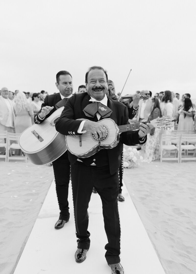 An intimate black-and-white wedding moment at the Royal Palms in Scottsdale, Arizona. The bride, elegantly dressed in lace, sips champagne while her groom drapes his jacket over her shoulders, capturing a timeless and romantic celebration.