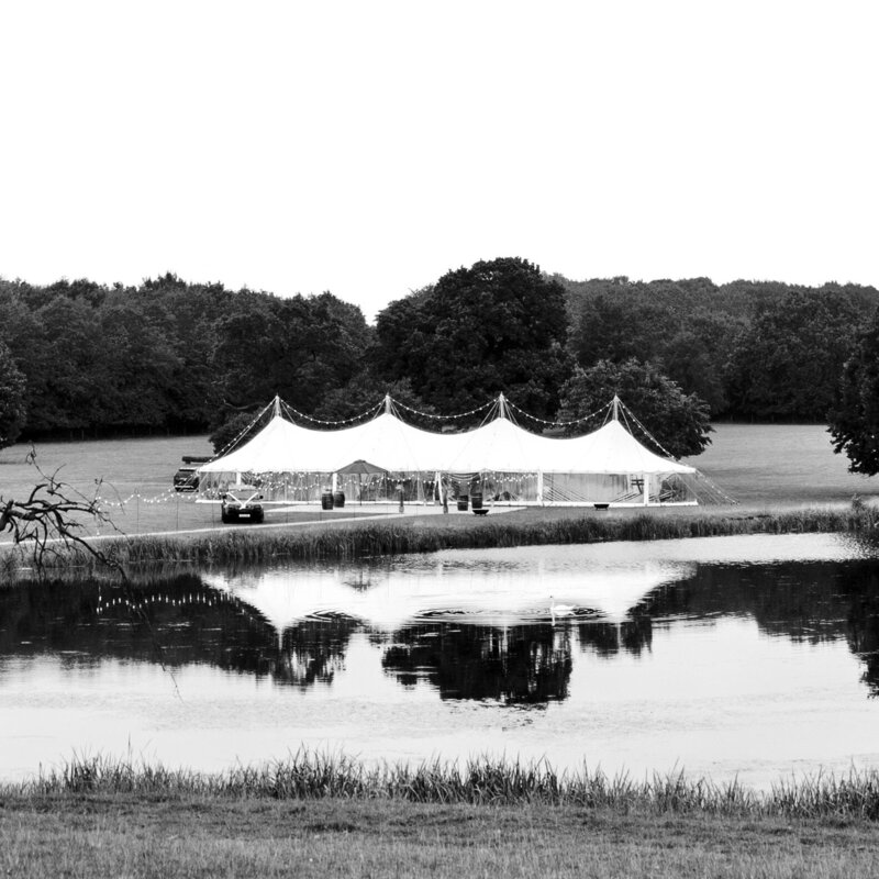 A black and white image of a pole marquee on beautiful grounds, taken from the air looking down