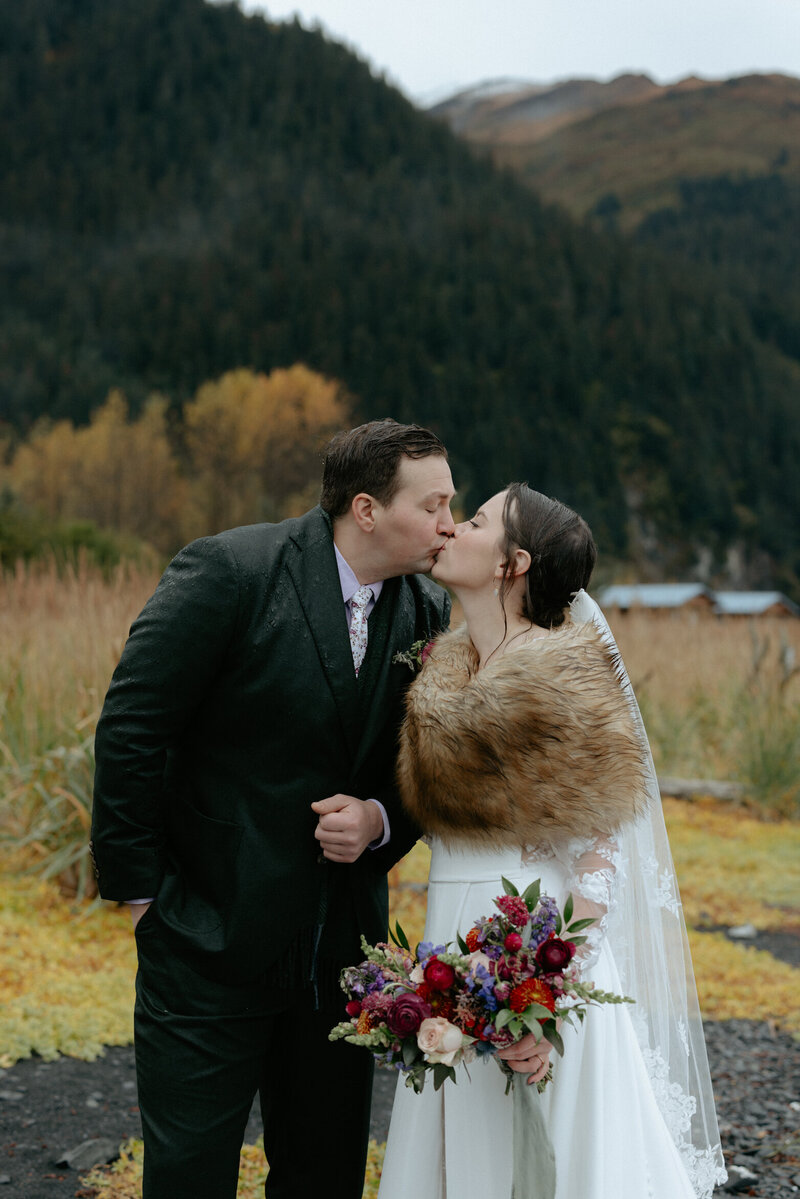 Couple kissing in front of the mountains.
