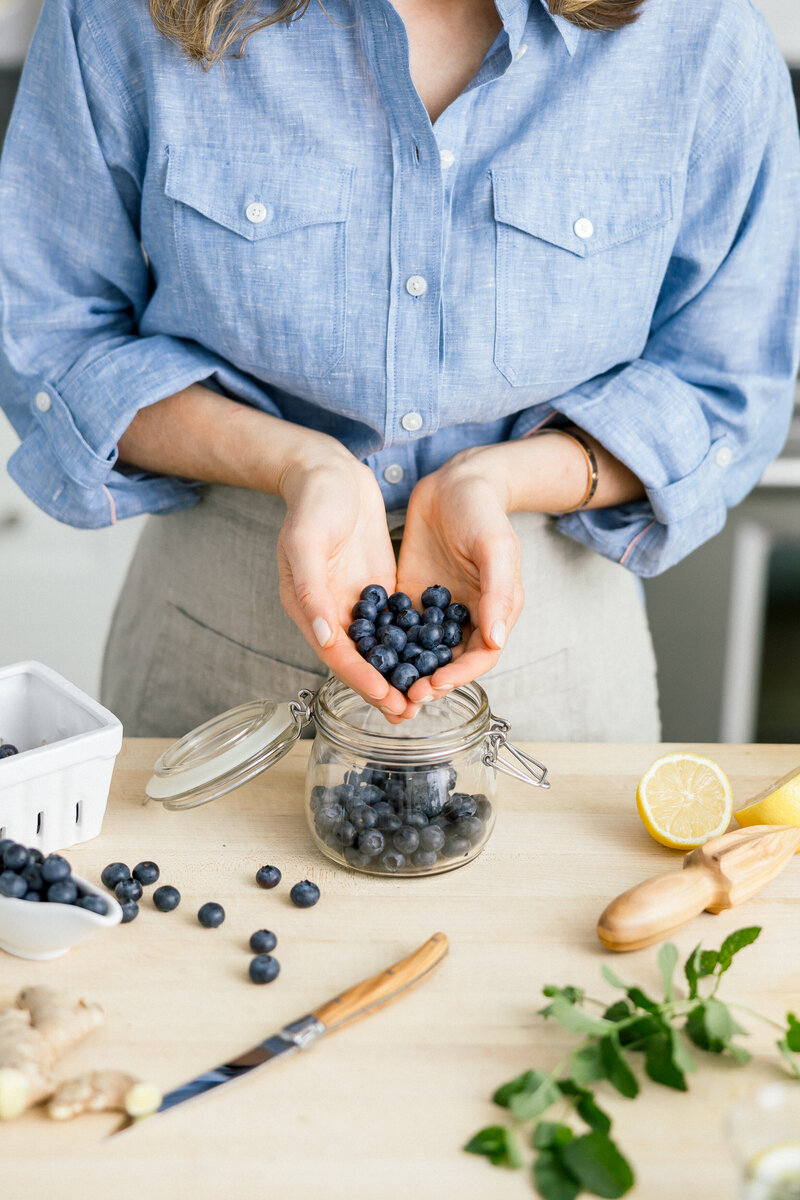 Influencer placing fresh blueberries in a kilner jar. 