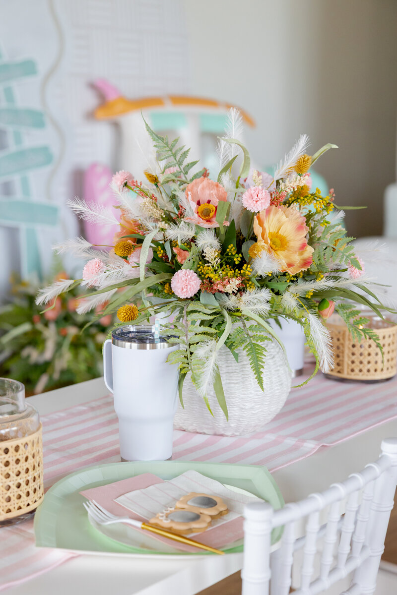Kids table decorated with beach flowers, tumblers and paper goods.