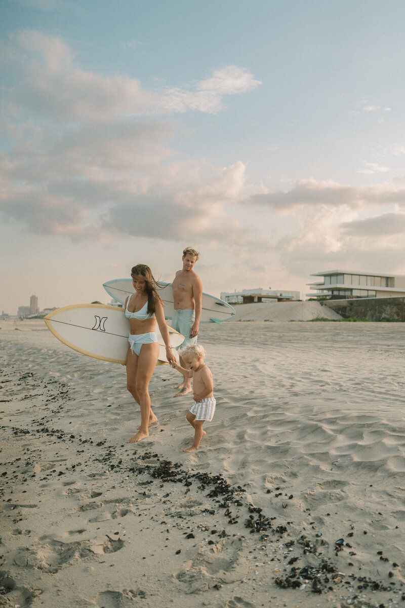 Family with surfboards walking on the beach. Maternity photographers nj, New Jersey Family photographers