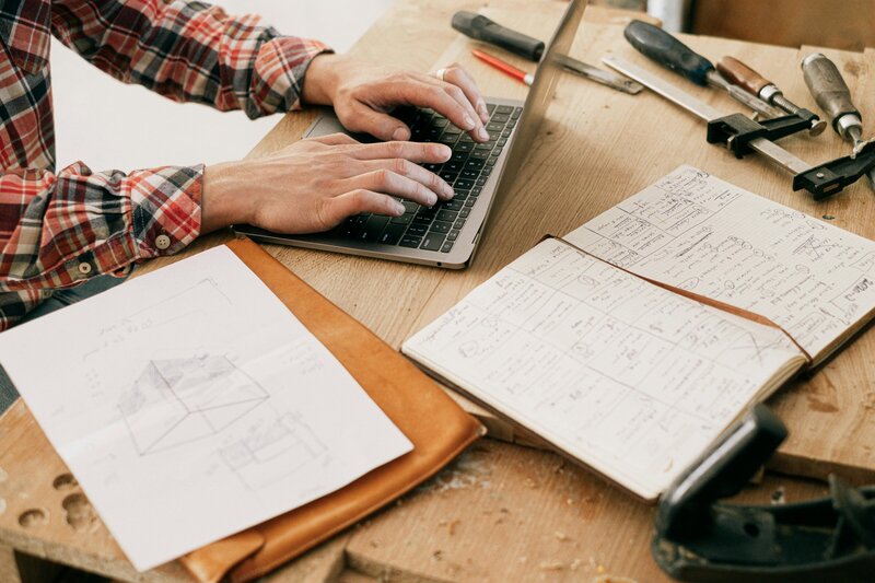 Man working on his laptop surrounded by tools