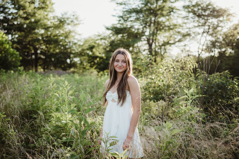 Senior girl surrounded by tall grass during a senior summer session. 