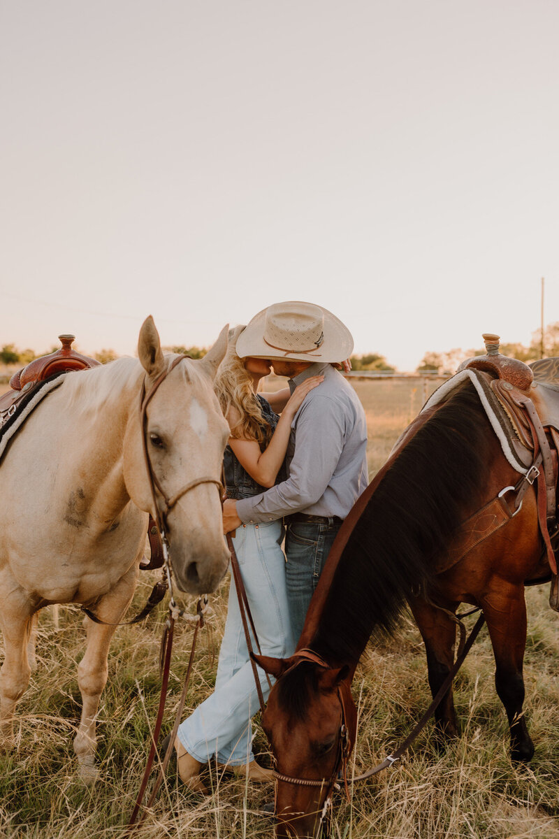 cowboy couple kissing with horses