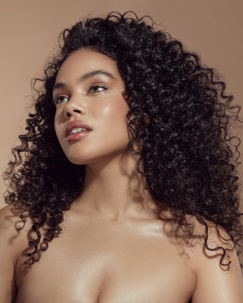Karina Dunbar with voluminous curls in a natural beauty portrait, exuding confidence and warmth, captured by Ylva Erevall.