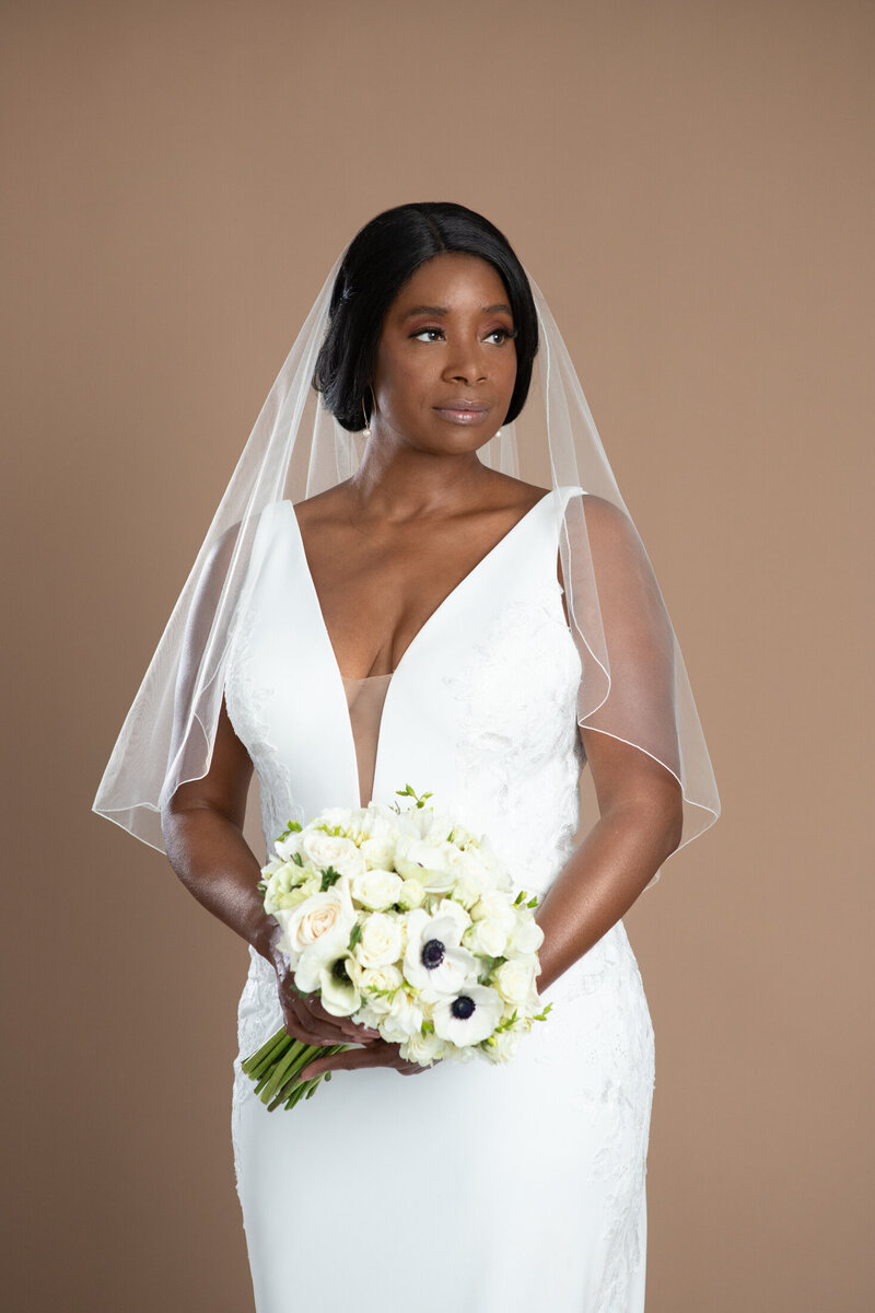 Bride wearing a fingertip length serged edge veil and holding a white and black bouquet