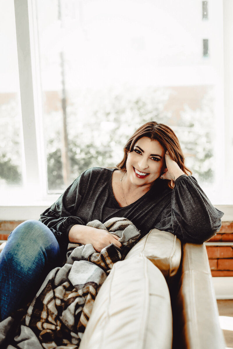Jan Touchberry sitting on green couch with Bible
