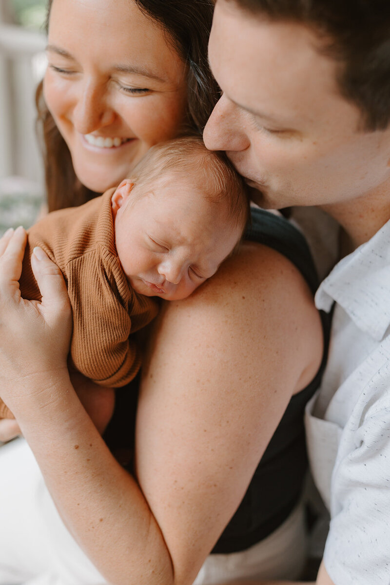 Parents smiling while holding newborn son in Webster Groves