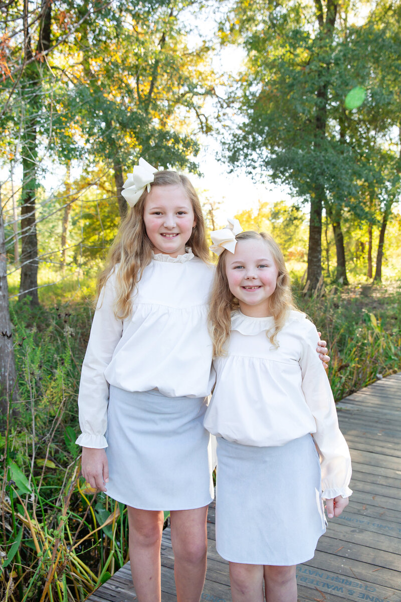Two girls in matching white tops and blue skirts