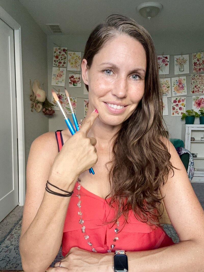 Woman in a red shirt painting a watercolor flower