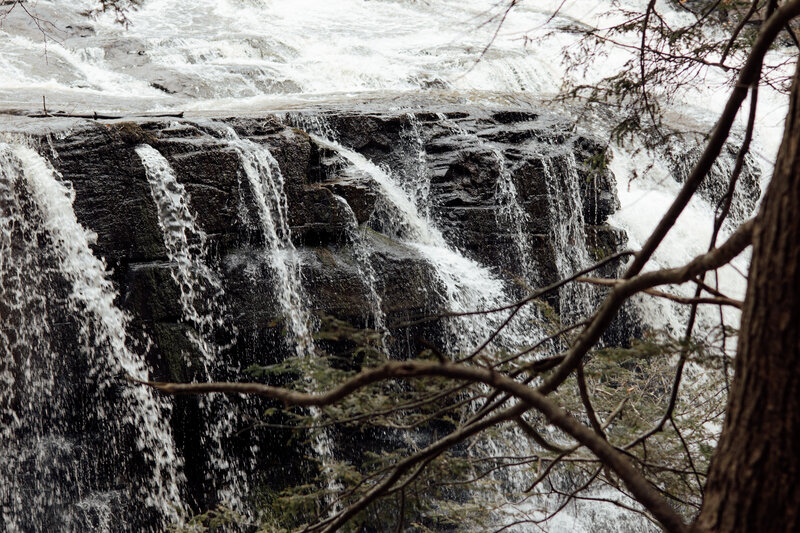 close up of a waterfall focusing on the water flowing over the edge of a boulder