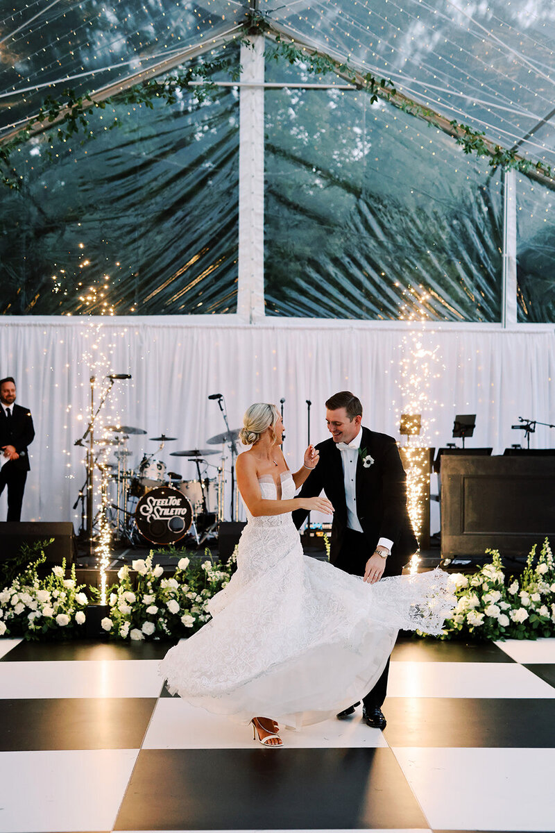 Brittany and Michael dancing the night away at their wedding at Boxwood Estate. While dancing on the checkered dance floor, surrounded by white roses, with sparklers on either side of them. 