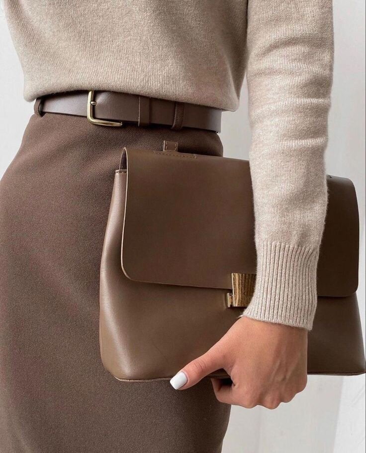 mid section shot of women dressed in a taupe pencil skirt, matching belt, an oatmeal colored sweater holding a taupe clutch with gold detail, funny bunny nail polish