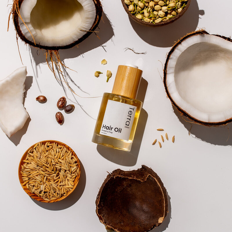 flat lay with hair oil surrounded by ingredients and coconuts