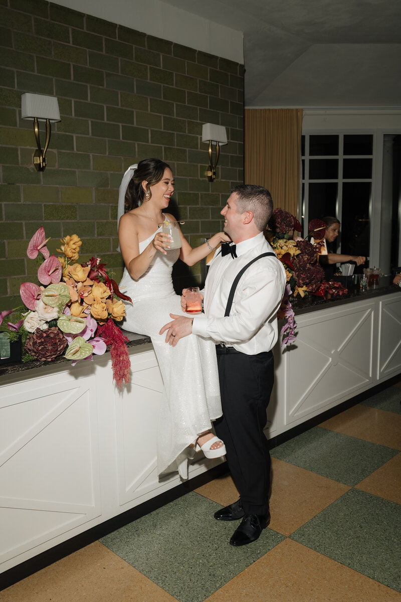 Bride and groom sitting on bar at their wedding reception at the Riviera Ballroom in Lake Geneva.