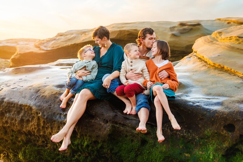 Young family snuggling on the beach in San Diego