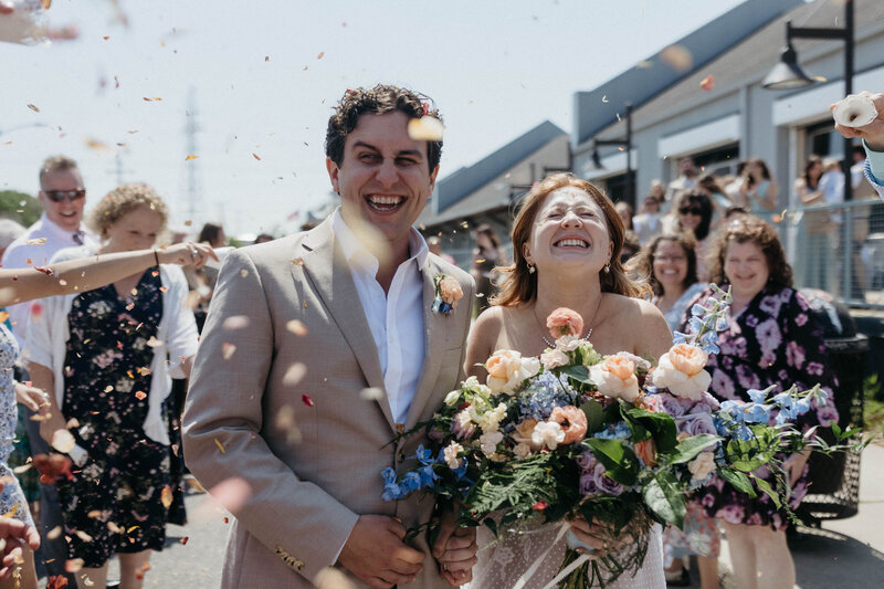 couple walks through flower petal confetti at end of their wedding