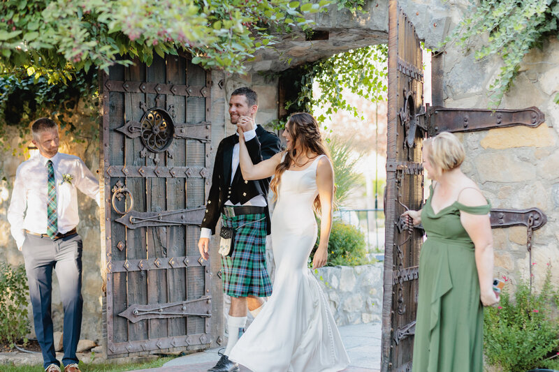 The newly married couple walks through large wooden doors