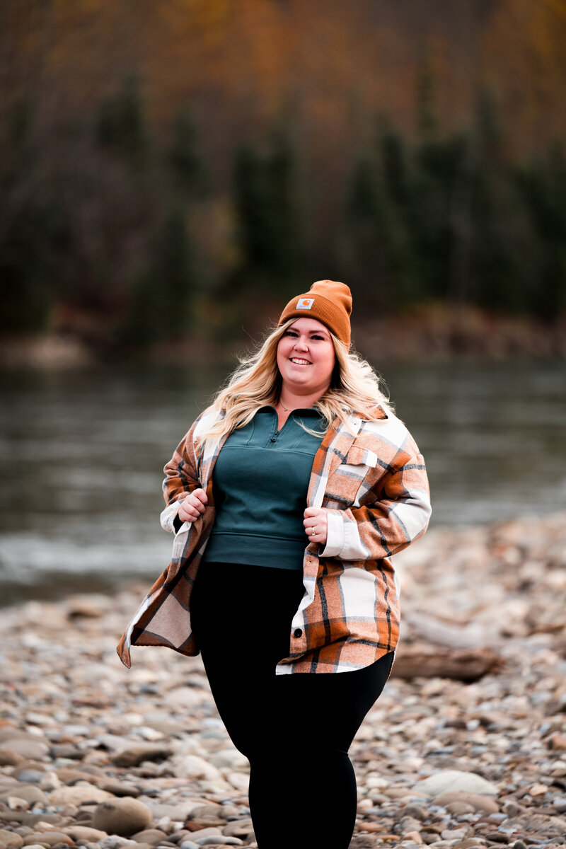 Edmonton wedding photographer smiling at the camera in front of river