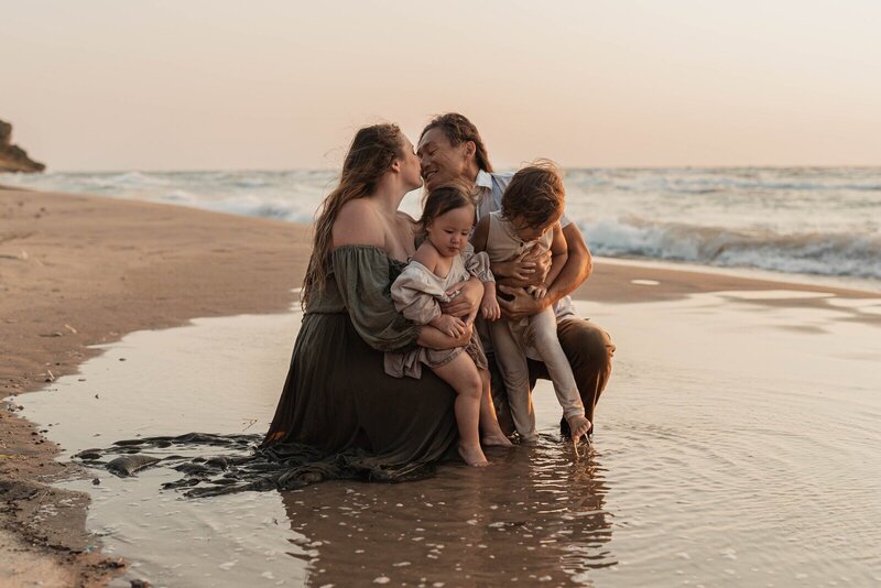 Family cuddling at golden hour on the beach captured by family photographers in Grand Rapids MI