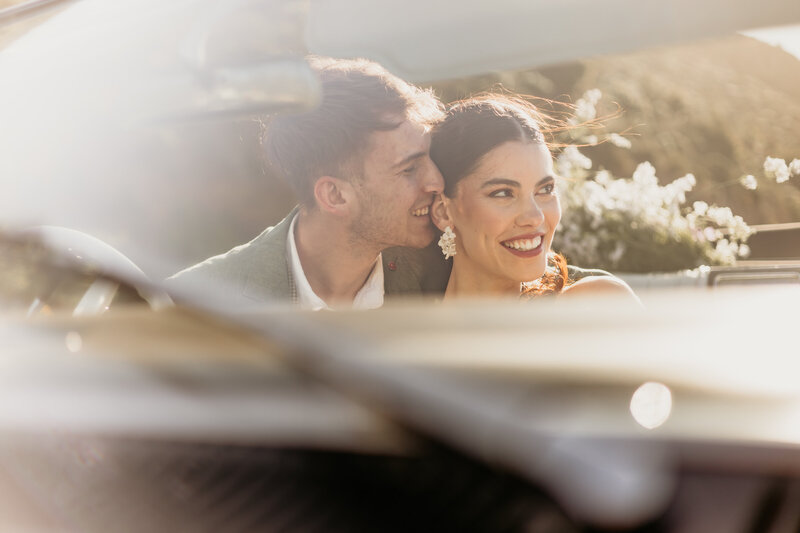 Hochzeitspaar auf dem Chapmans Peak in Kapstadt bei Sonnenuntergang im Oldtimer