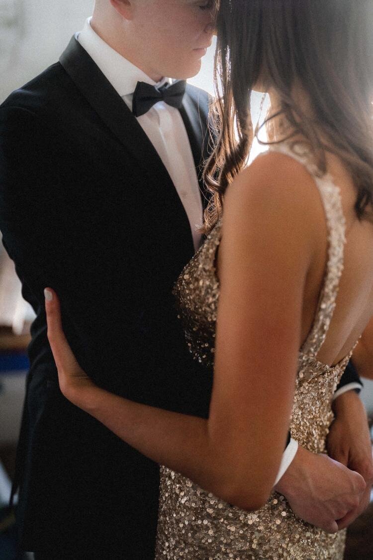 Bride and groom hugging. Bride is wearing a gold Dress