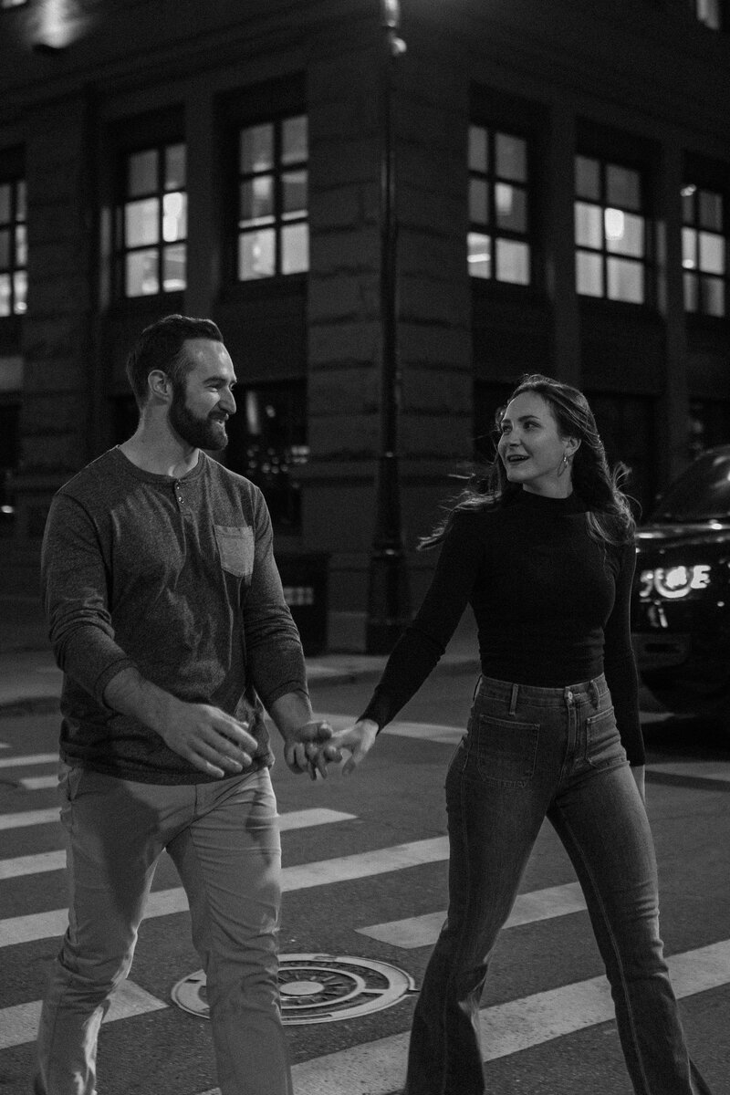 A couple holding hands and walking across the street 