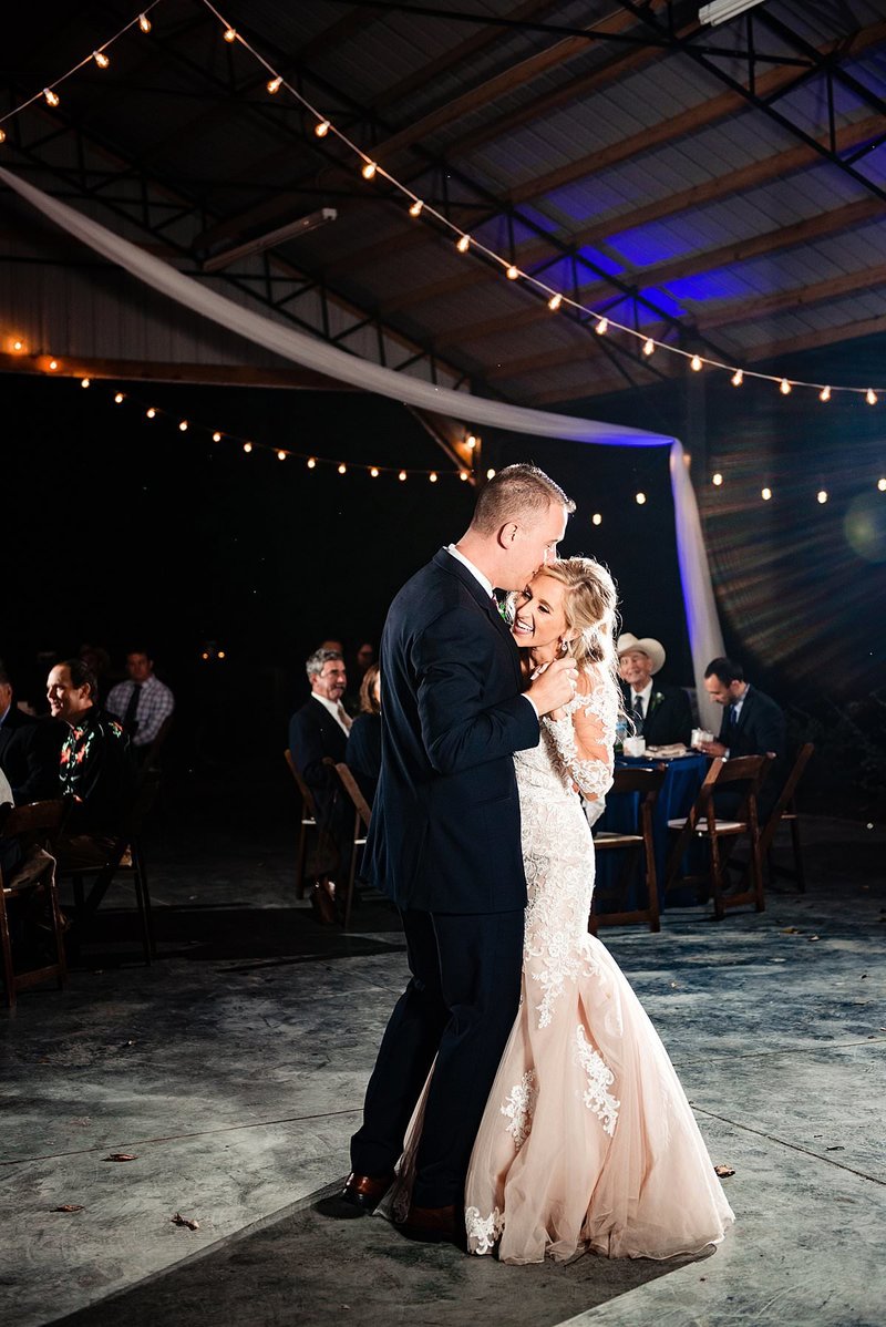 Romantic photo of bride and groom sharing their first dance at night with string lights above them