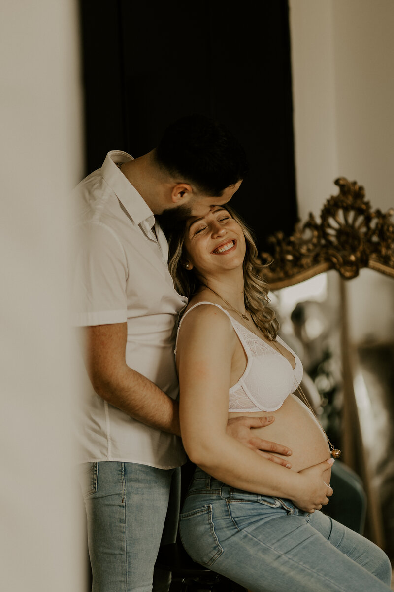 Couple s'embrassant, tenant leur bébé dans leurs mains, capturé dans mon studio photo en Vendée.