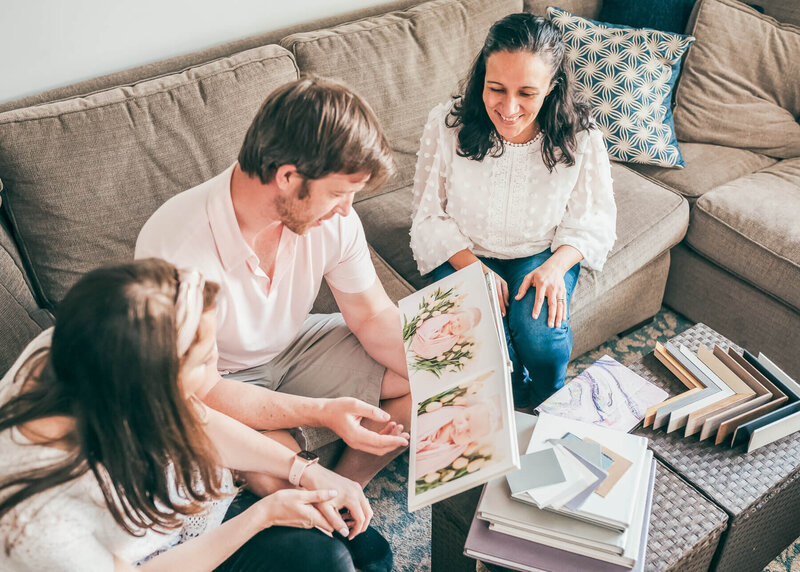 A photographer sitting with a couple while looking at an album