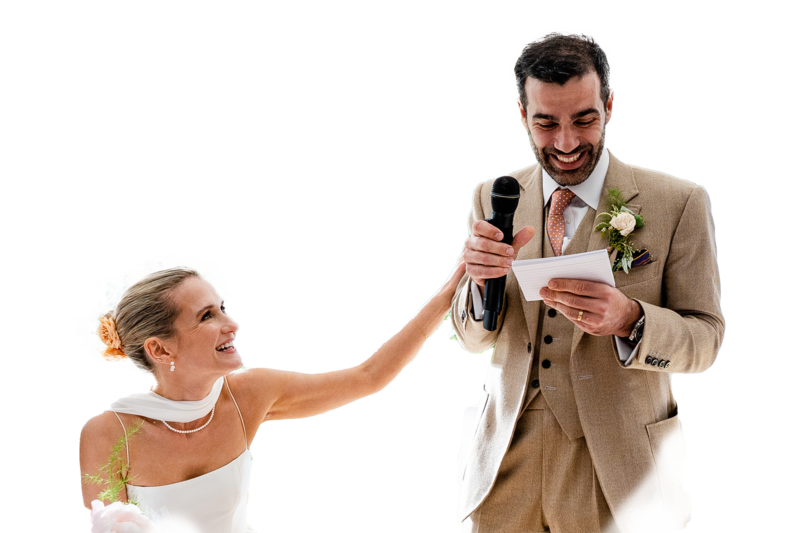 a photograph of a couple during their speeches, the groom is getting emotional and the bride places a hand on his arm in comfort.