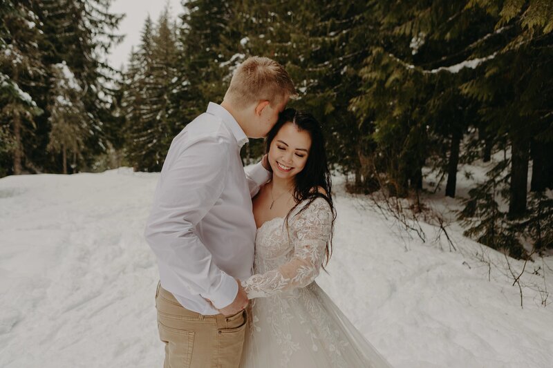 couple embraces and kisses in shrubbery outside