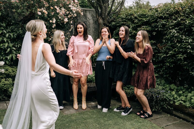 a group of women see a bride for the first time and its emotional in a garden in the city