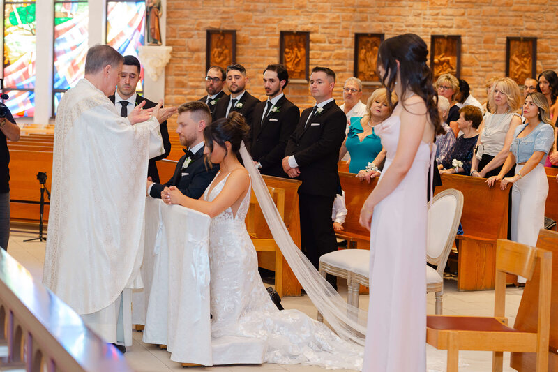Ottawa wedding photos showing the priest blessing the bride and groom just after their vow exchange