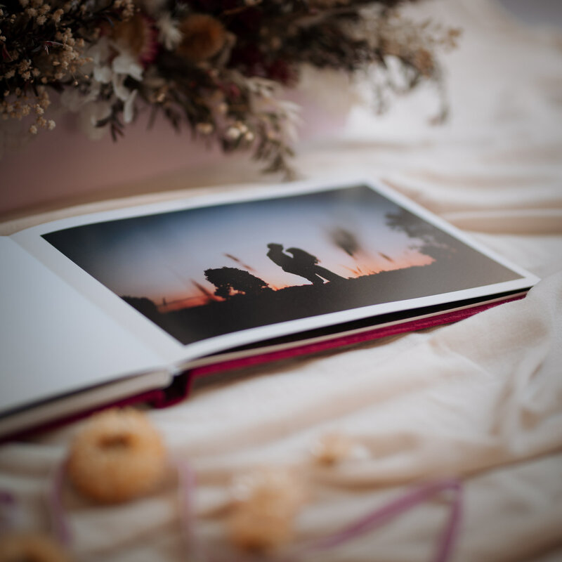 Open page of guest book displaying silhouette of couple kissing at sunset