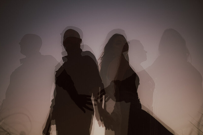 A man and a woman standing back to back with multiple other images of them overlayed behind it in various transparencies