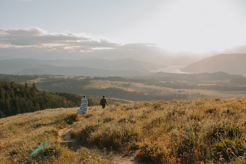 Bride and groom hiking down grassy hillside