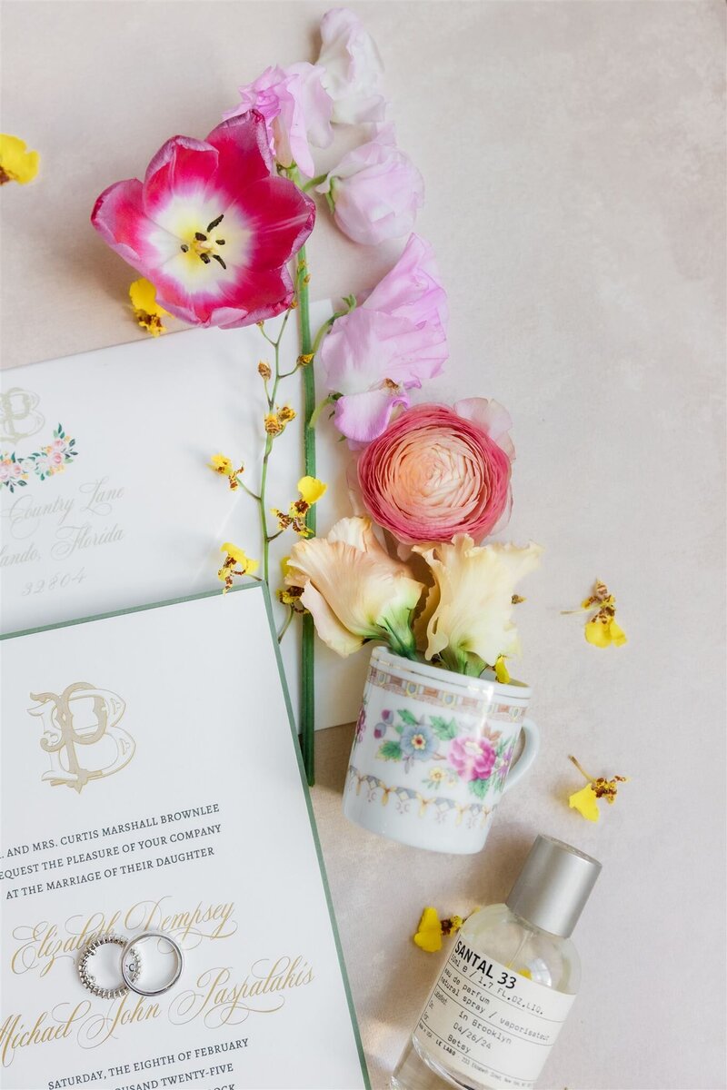 Photo of bride's flatlay details with bright and colorful blooms and a gorgeous invitation suite