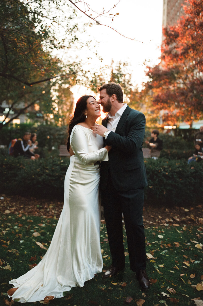 Film photo of a couple sharing a joyful moment during their fall wedding in the Boston Public Garden, surrounded by golden leaves and soft evening light — documented by a film wedding photographer.