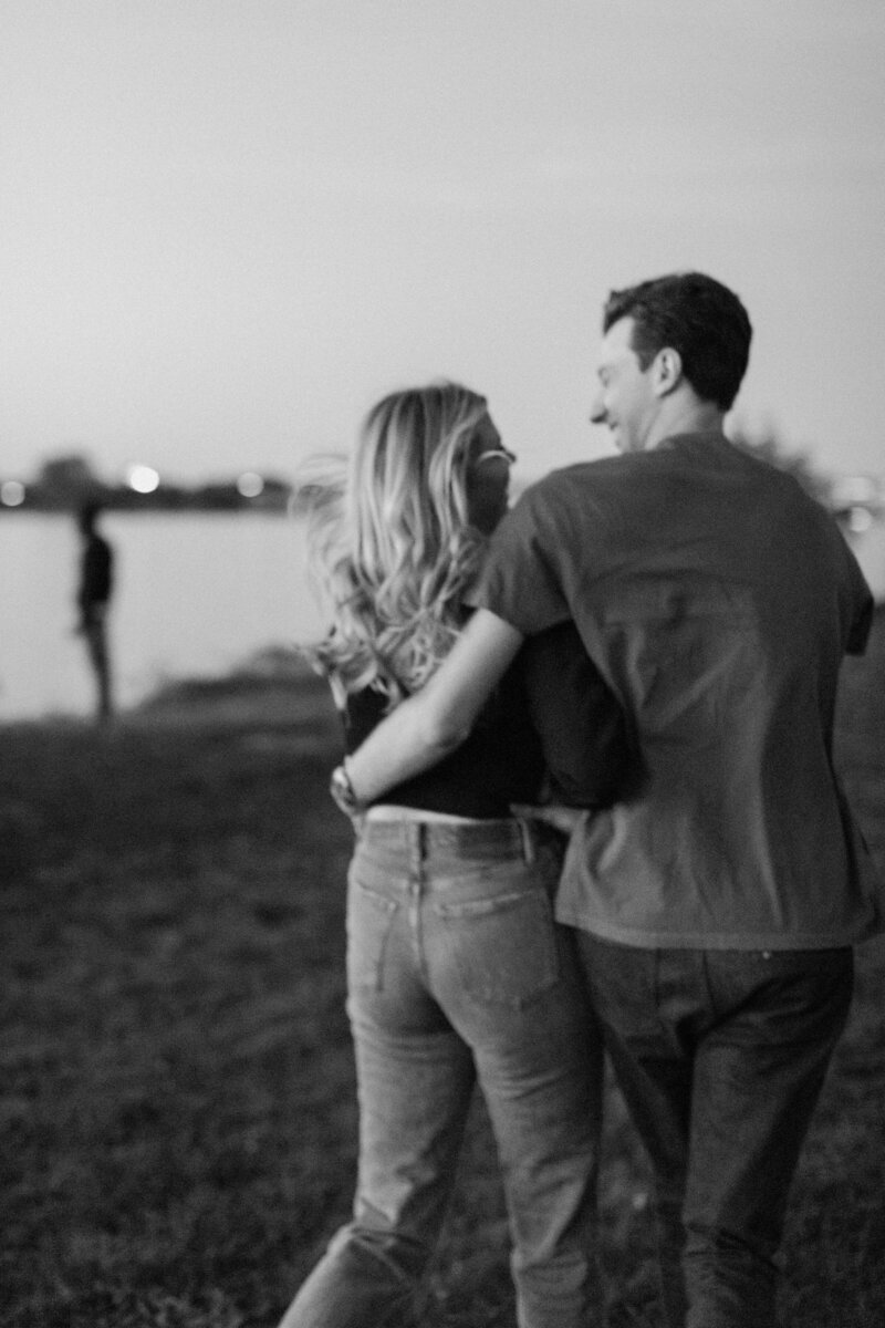 a young couple running away from the camera with arms wrapped around each other laughing