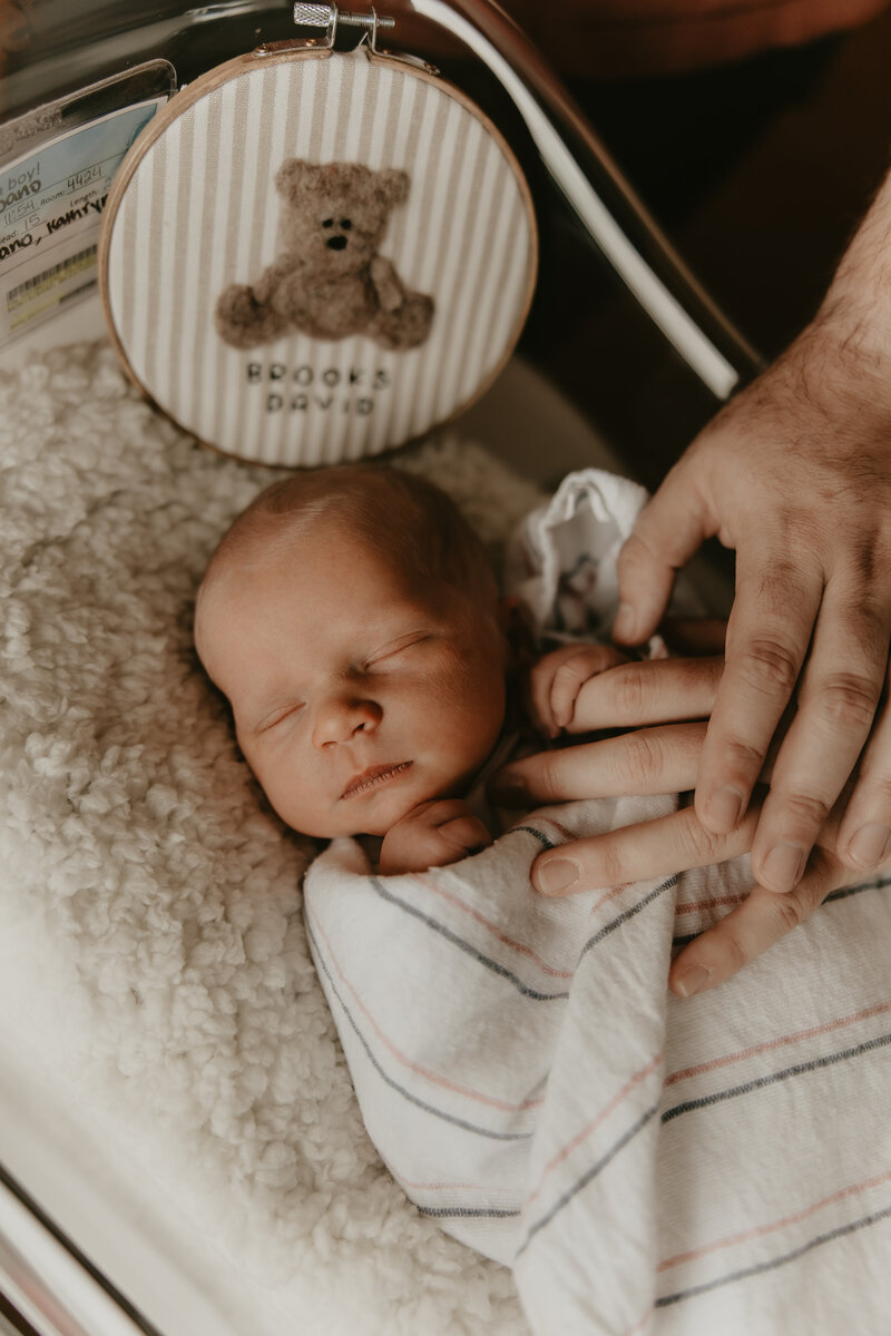 Cozy in-home newborn photography session in Morristown, New Jersey featuring parents and older brother lovingly holding their baby in soft natural light gazing lovely at each other.
