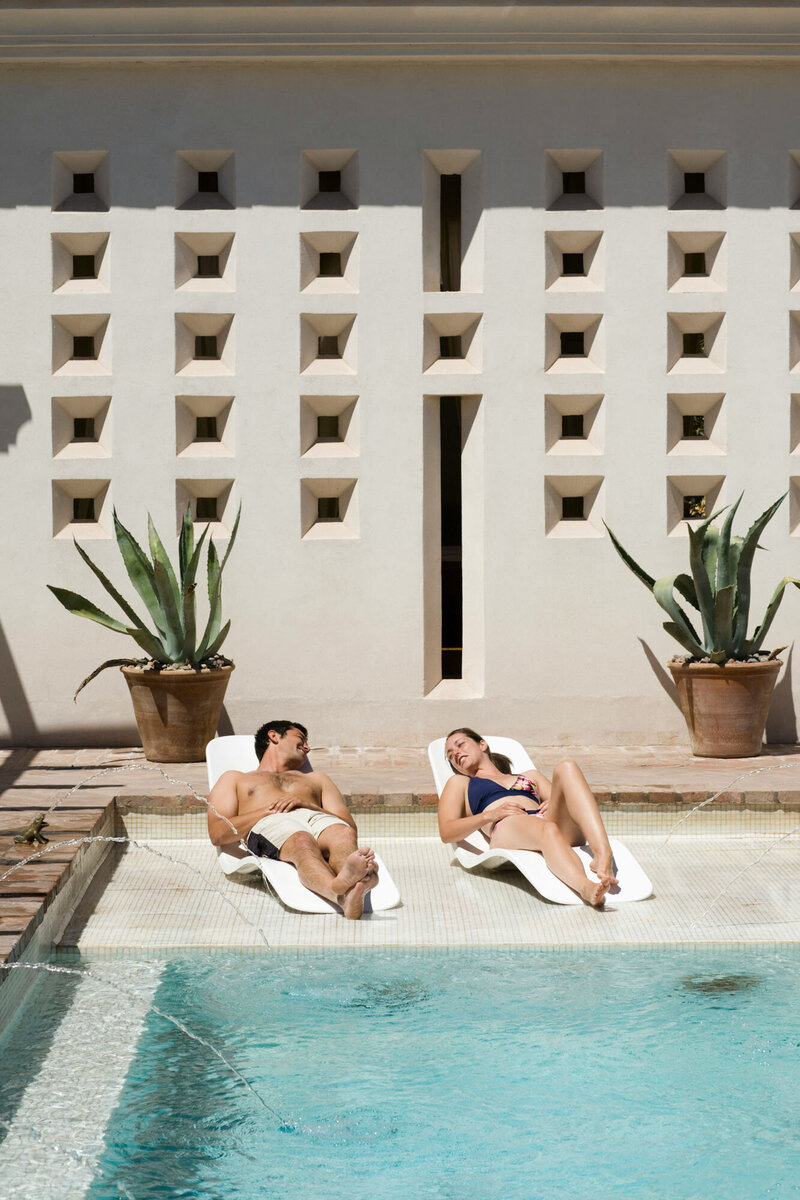 Man and woman are laying by a swimming pool