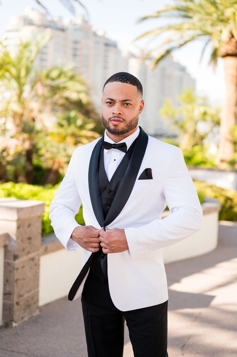 Groom adjusting cufflinks in classic black tuxedo from Men’s Warehouse at Emerald at Queensridge.